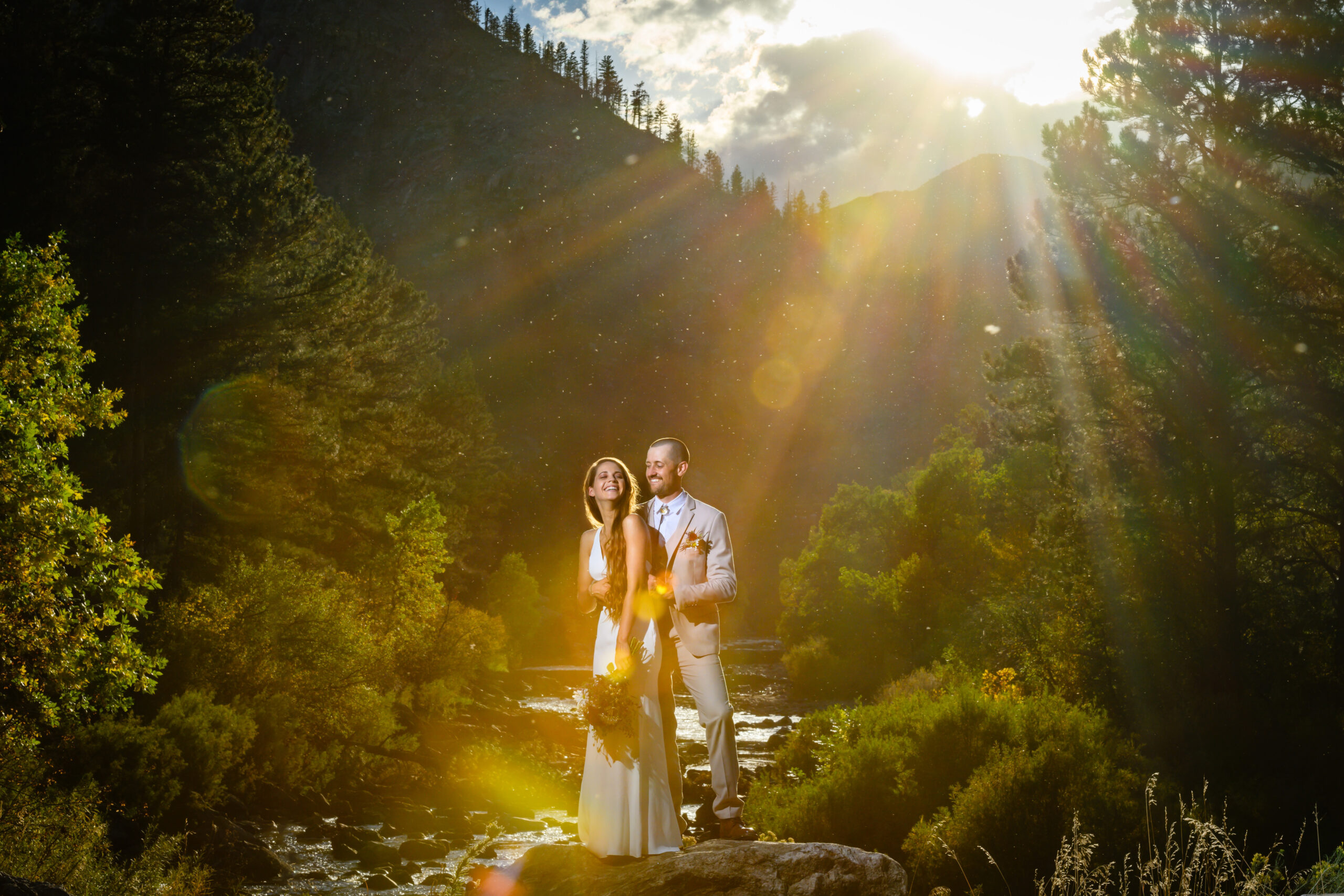 A couple on their wedding day illuminated in light by a river in Estes Park, Colorado