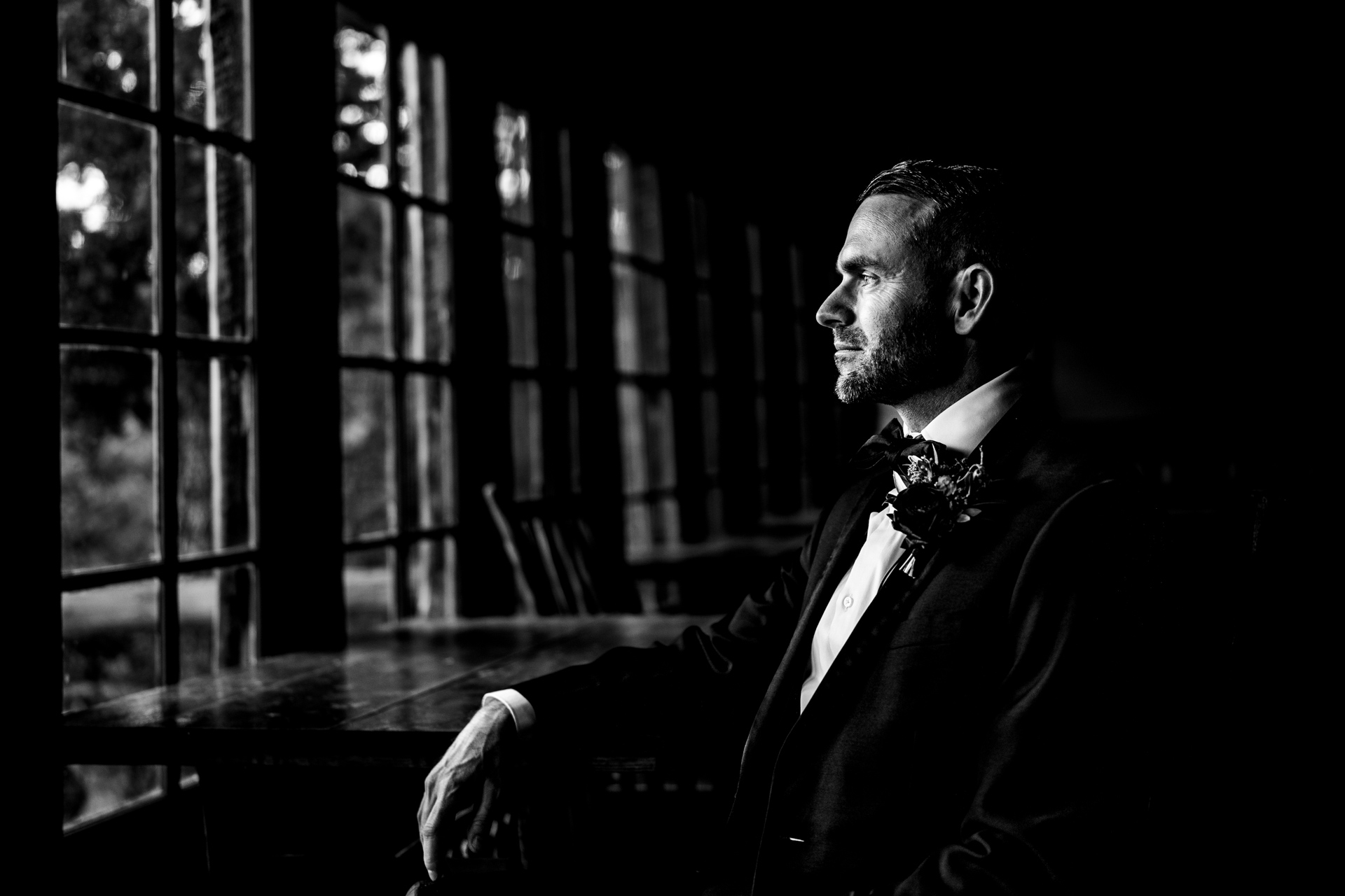 Groom contemplates his wedding day out windows overlooking the mountains.