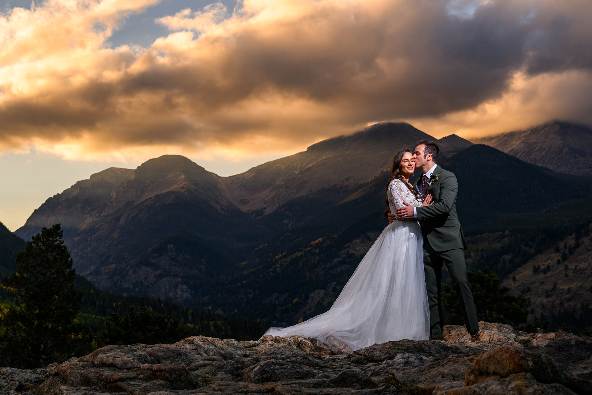 The bride catches a kiss from the groom on the top of the mountains of Rocky Mountain National Park