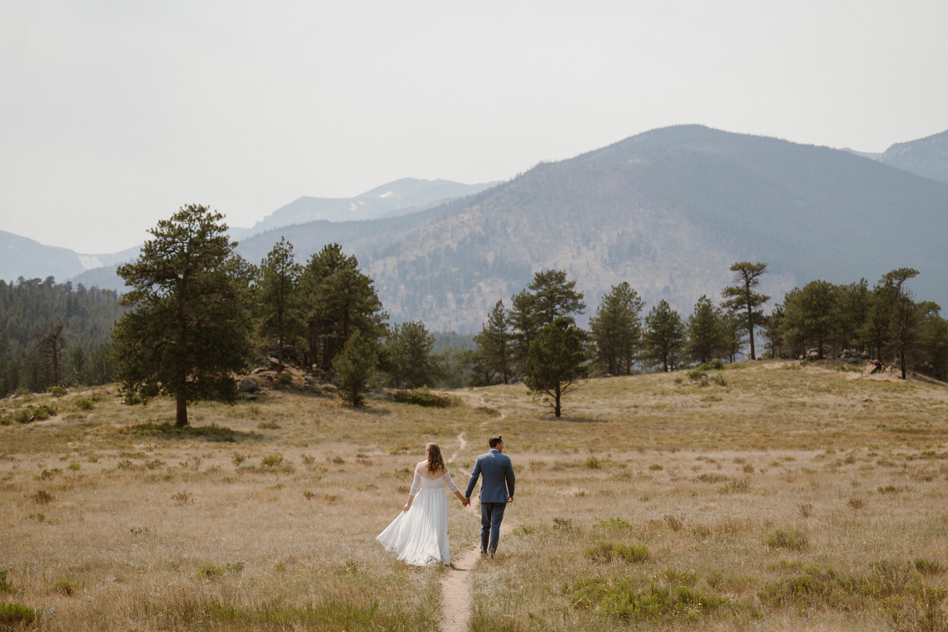 Bride and groom walk into the mountains of Estes Park, Colorado