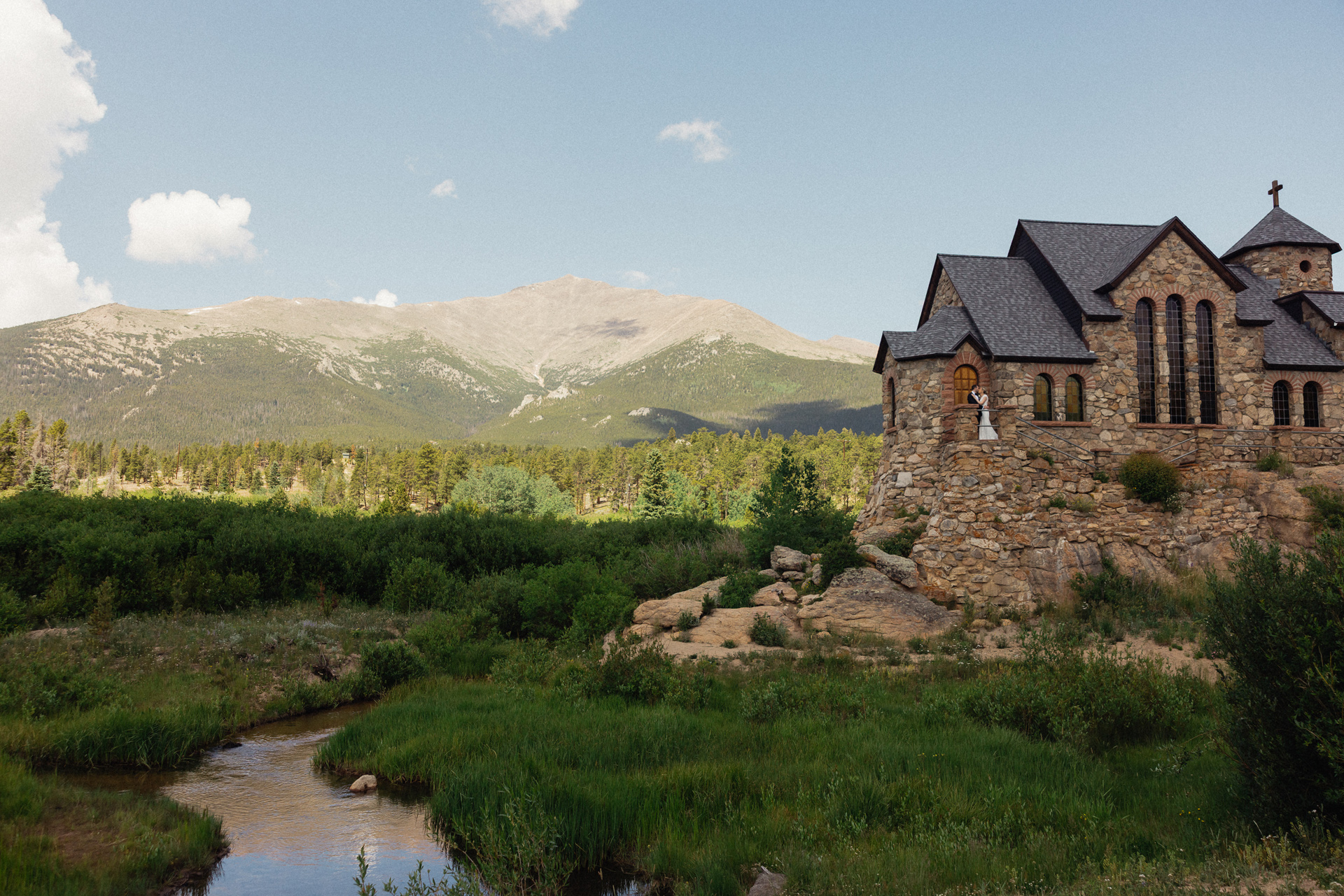A wedding day couple at St. Malo's Church with Mt. Meeker in Allenspark, Colorado